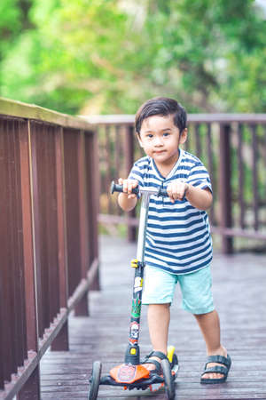 Cute little Boy is playing a scooter in a park.Image with Grainの写真素材
