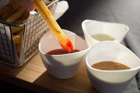 French fries in a metal basket with sauce on a wooden floor.の写真素材