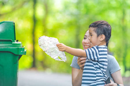 Cute little boy are dumping trash in a recycle bin,concept of teaching children to love the environment.Soft focus and Image with Grain.の写真素材