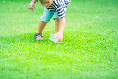 Boy keeps plastic water bottle on grass.The concept teaches children to preserve the environment.