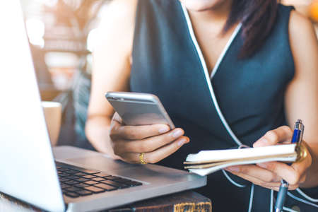 Businesswoman working in office,She holds a cell phone and notepad.の写真素材