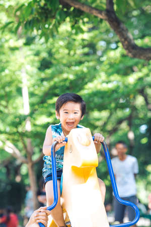 An Asian boy is playing a rocking horse in an outdoor playground.He enjoyed playing,Soft focus and Image with Grain.の写真素材