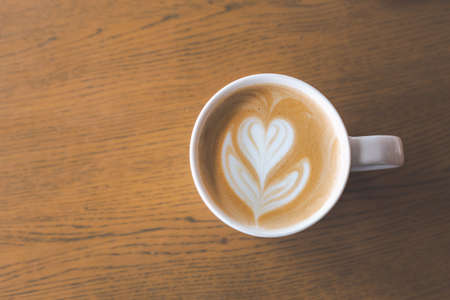 Latte coffee art in white cup on wooden backgroundの写真素材