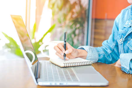woman's hand works in a notebook and is writing on a pen notepad in the office.の写真素材