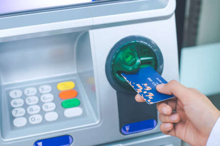 woman's hand inserting debit card into an ATM machine
