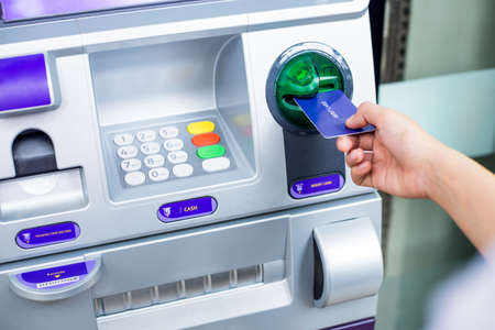 woman's hand inserting debit card into an ATM machineの写真素材