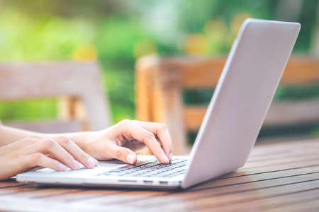 Woman hands working with laptop computer in cafe in the garden in front of the office. Soft focusの写真素材