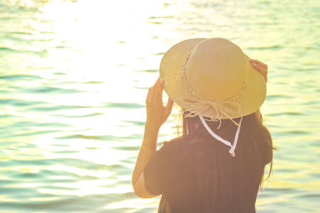 Women wearing a hat are enjoying a beautiful sunset on the beach.Vintage toneの写真素材