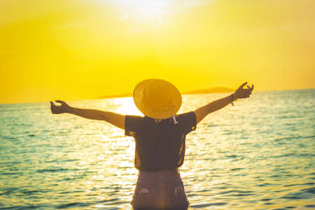Women wearing a hat are enjoying a beautiful sunset on the beach.