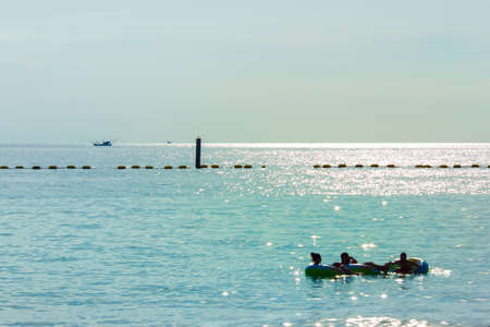 Beaches at sunset and floating people on rubber rings.の写真素材