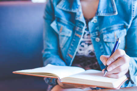 Woman hands with pen writing on notebook in the office.の写真素材