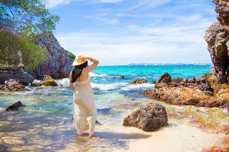 Woman in a cream dress is standing, enjoying the beautiful sea on the beach.の写真素材