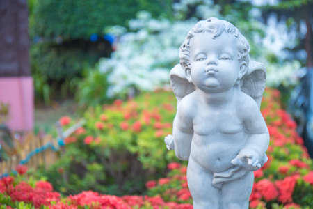 Cupid stone statue in the flower garden.の写真素材