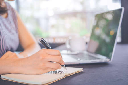 Business woman hand writing on notepad with a pen in the office.の写真素材