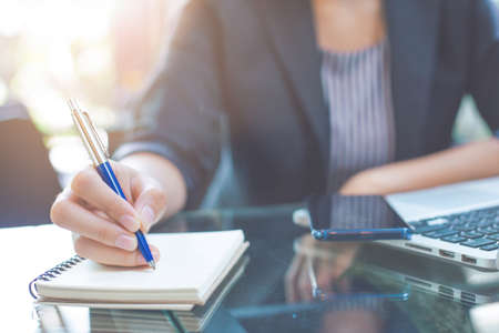 Business woman writing on a notebook
with a pen in the officeの写真素材