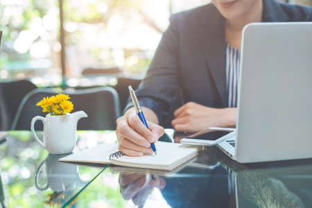 Business woman writing on a notebookwith a pen in the officeの写真素材