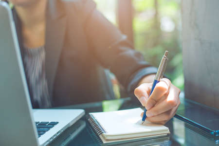 Business woman writing on a notebook
with a pen in the officeの写真素材