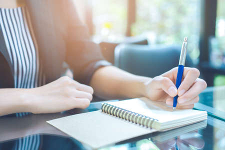 Business woman writing on a notebook
with a pen in the officeの写真素材