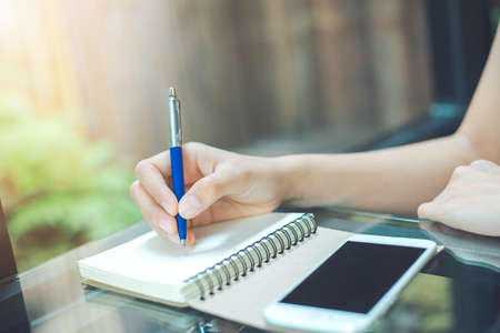 Business woman writing on a notebook
with a pen in the officeの写真素材