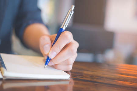 Business woman hand writing on a notebook with a pen in the office