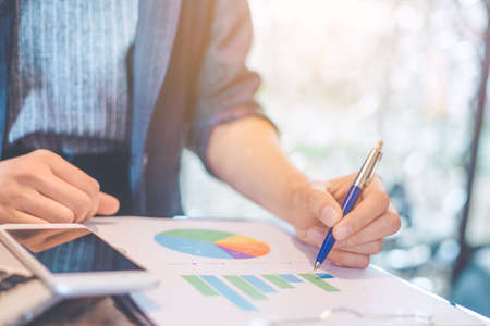 Business woman hand writing on charts and graphs that show results.