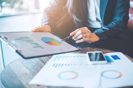 Business woman hand work on charts and graphs that show results.She uses the pen to point to the...
