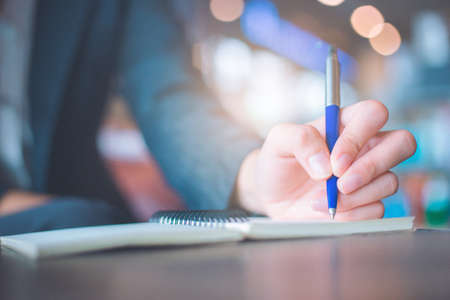 Business woman hand  writing on a notepad with a pen in the office.