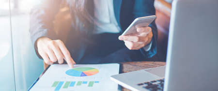 Business woman hand uses a phone to work on charts and graphs that show results.Web banner.の写真素材