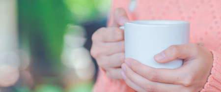Woman holding a cup of coffee on handの写真素材