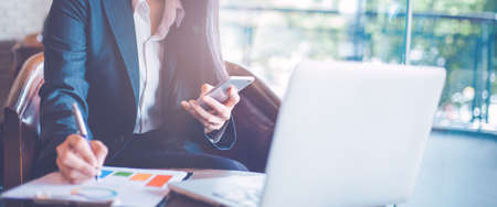 Business  woman uses a smartphone and writing on charts and graphs that show results.Web banner.の写真素材