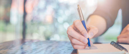 Woman hand writing on a notepad with a pen in the office.Web banner.の写真素材