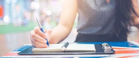 Woman hand writing on a notepad with a pen.Web banner.