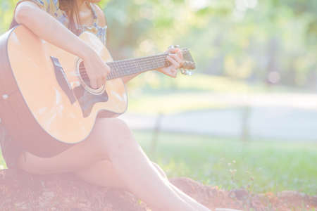 Woman is playing acoustic guitarr in the garden.の写真素材