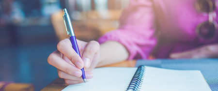 Woman hand taking notes on a notebook using a pen.Web banner.
