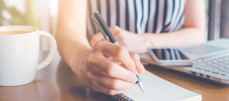 Business woman writing on a notepad with a pen and working at a compute.Web banner.の写真素材