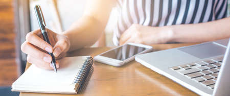 business woman working at a computer and writing on a notepad with a pen..Web banner.の写真素材