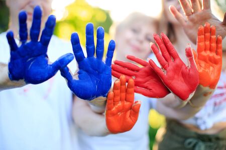 Hands of family members in paint. Playing with paints outdoors.