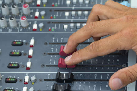 An expert adjusting audio mixing console.select focus