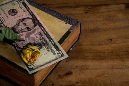 Put money on a book on old wooden floor.still lifeの写真素材