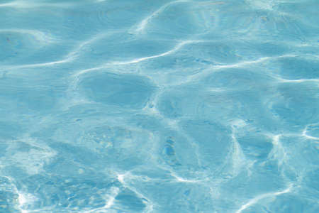 Blue pool water with sun reflections.