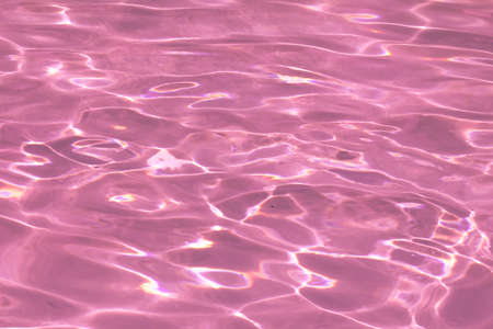 pink pool water with sun reflections.の写真素材