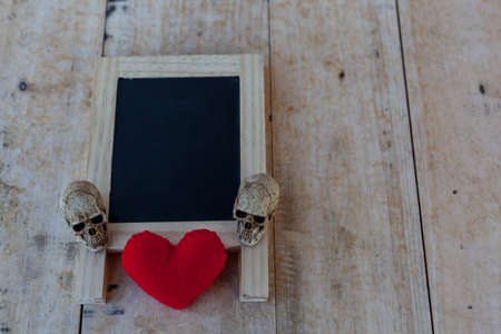 Menu board in black and red heart and a human skull lay on the wooden floorの写真素材