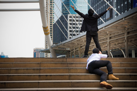 Turn on Asian businessman's who raising his two hands. Business people make a successful in his career and mission. He is a winner of the competition and the loser try to climb on the step to the goalの写真素材