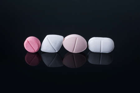 Medical pills with various shape, size and color on black surface with reflection.Studio shot.の写真素材