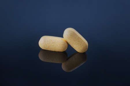Medical pills and supplement capsule on black table with reflection.の写真素材