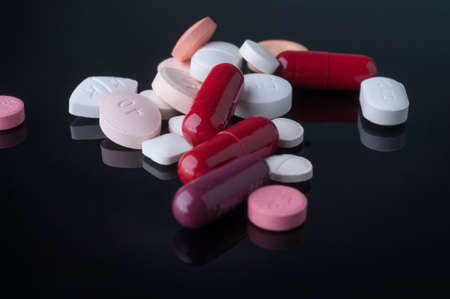 Medical pills and supplement capsule on black table with reflection.の写真素材