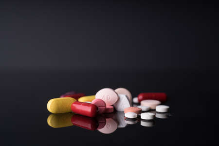 Medical pills and capsules on black background with reflection.の写真素材