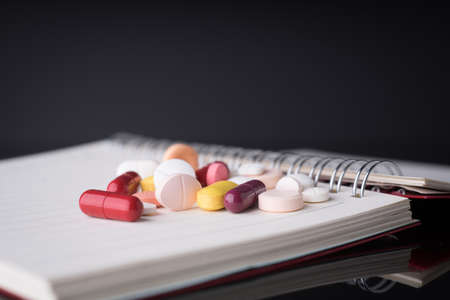 Medical pills on notebook with black backgroundの写真素材