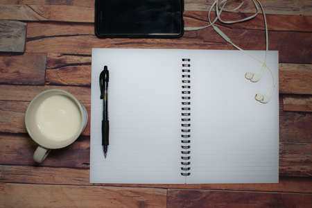 A cup of milk,pen and a blank note book on the wooden table .View from top with copy space.の写真素材