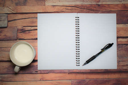 A cup of milk,pen and a blank note book on the wooden table .View from top with copy space.の写真素材